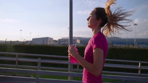 Woman Running with Water Bottle on Track