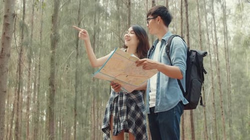 Asian hiker couple trekking in forest. Young happy backpack male and female walking.
