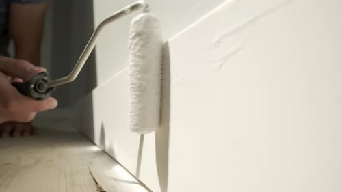 Painter Applies White Paint to Baseboard Trim