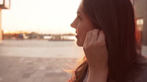 Woman Puts Earbuds In at Golden Hour