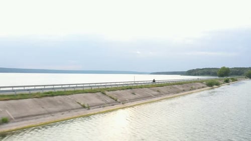 Aerial Shot of Motorcyclist Racing His Motorcycle Through Road Near Lake