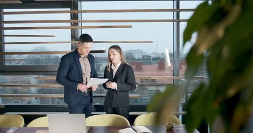Man and a Woman Discussing Work in the Brightly Lit Modern Office. Concerned Male and Female Working