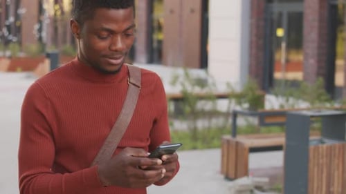African American Businessman Using Smartphone during Walk in Downtown
