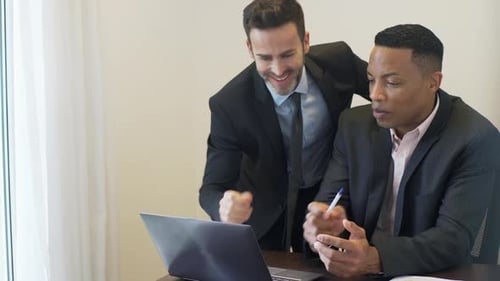 Businessmen Collaborating on Laptop in Bright Workplace