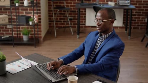 Focused Man Working on Laptop in Modern Office