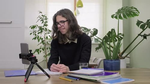 Male Teenage High School Student at Home Looking at Smartphone Camera Studying Online