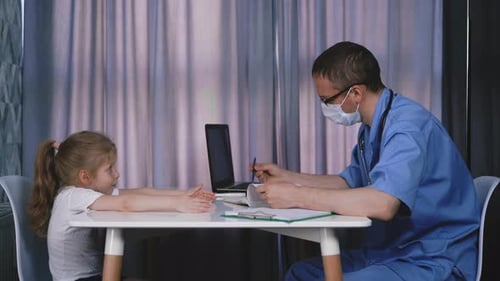 Doctor in Uniform and Mask Examines Little Girl in Office