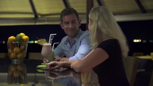A man and woman couple have a drink at a bar at a resort