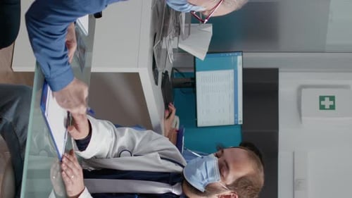 Doctor Reviews Patient Record at Clinic with Masks