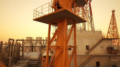 Luftdrohnenaufnahme einer Offshore-Ölplattform im offenen Meer bei Sonnenuntergang.