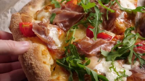 Prosciutto-Pizza mit Strachatella-Käse, Tomaten und Rucola-Blättern