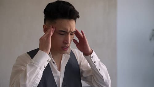 Young Asian Man Massages Temples Suffering From Headache