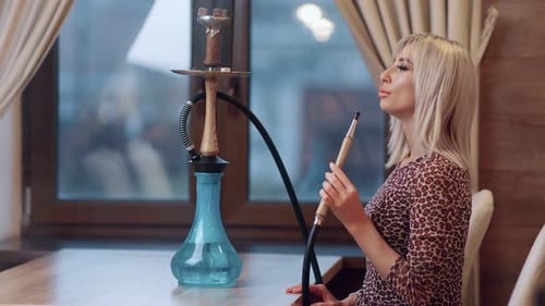 Charming Trendy Woman Smoking Shisha Sitting in Lounge Bar