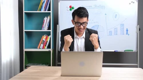 Young Man Celebrates Business Success in Home Office