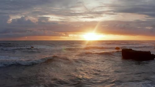 Ocean Waves Crashing on Rocky Shore During Sunset