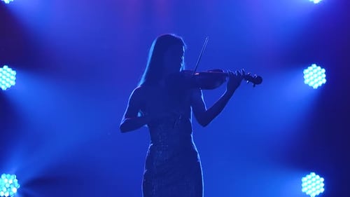 Silhouette of Violinist Performing on Stage with Blue Lights