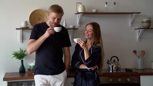 A Family Man and Woman Stand in the Morning in a Modern Kitchen, a Couple Drink Coffee, Chat and