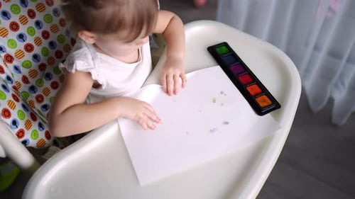 Child Finger Painting at Home in High Chair