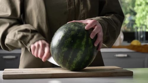 Mann schneidet Wassermelone auf Schreibtisch in der Küche