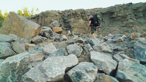 Man Climbing Rocky Hill in Outdoor Wilderness Area