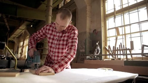 Concentrated Caucasian Male Carpenter Using Jigsaw Tool to Cut Wooden Workpiece in Joinery
