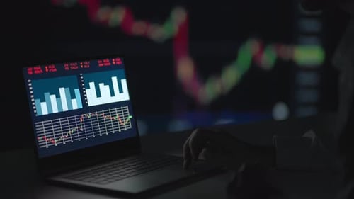 Analyzing Stock Market Charts on Laptop at Night