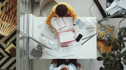 Top View of Male and Female Colleagues Discussing Architectural Plan