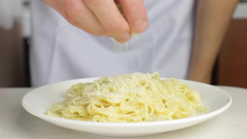 Adding Cheese to Delicious Pasta Dish Close Up