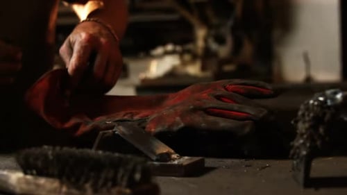 Man Putting on Protective Gloves at Workbench