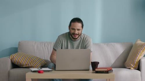 Man Using Laptop and Waving Hello Indoors