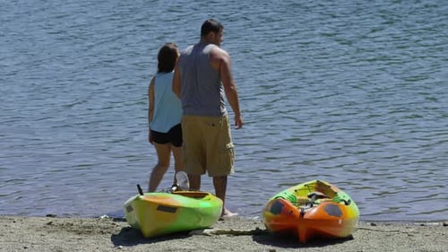 Couple with kayaks look out at lake