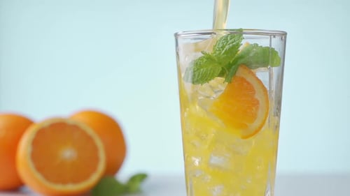 Orange Juice Being Poured into Glass with Ice