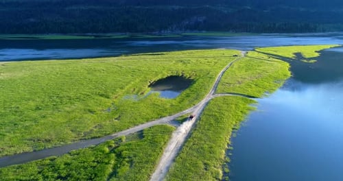 Vehicle driving on dirt road near lakeside