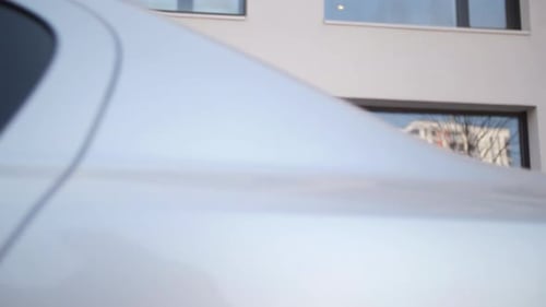 Una niña vestida de color beige camina por el edificio y el estacionamiento