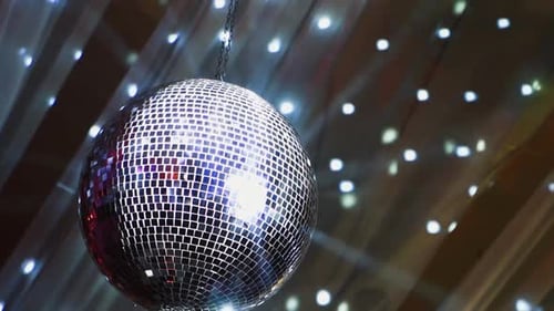 Mirror ball spinning slowly and shimmering. Round silver ball on the background with moving spots. S