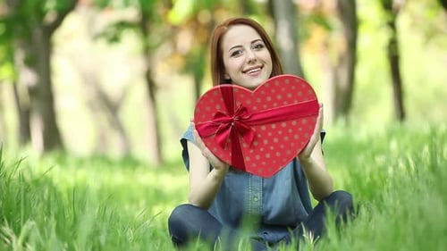 Smiling Woman with Heart-Shaped Gift in Green Park