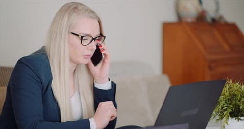 Woman Talking on Phone While Working on Laptop