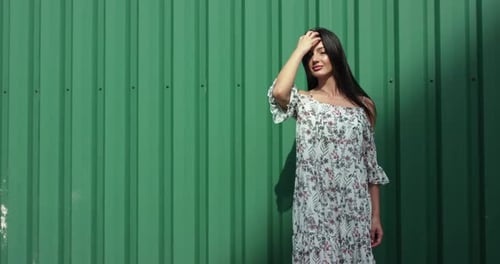Woman Posing in Floral Dress against Green Wall