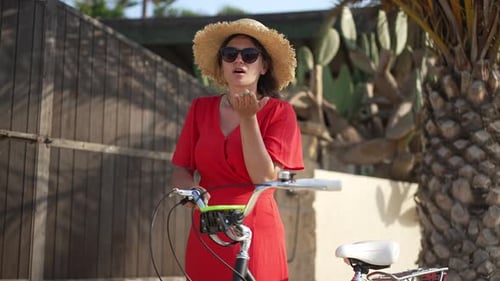 Coquette Caucasian Young Woman Gesturing Air Kiss Smiling Looking at Camera Standing with Bike