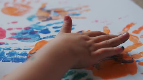 Child Makes Colorful Handprint Art on Paper