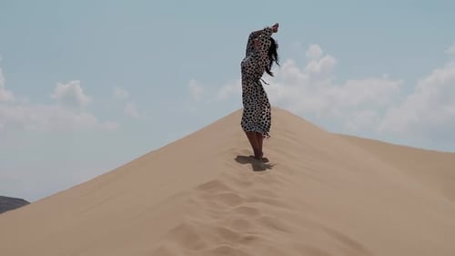 Girl in a Bright Dress Walking Barefoot Along the Dunes in the Desert