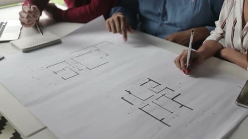 Ausgeschnittene Aufnahme von Architekten, die Blaupausen studieren