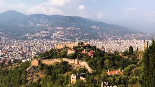 Vista aérea de la ciudad y el castillo escondidos entre árboles y plantas verdes. Pan de tiro a la derecha