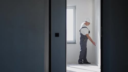 Ein Elektriker in einem Helm installiert und überprüft LED-Streifen auf Beleuchtung in der Wohnung