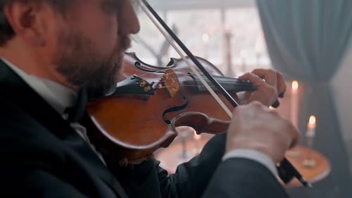 Musician Plays Violin in Candlelit Room