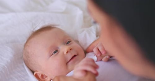 Happy Infant Playing with Parent on White Blanket