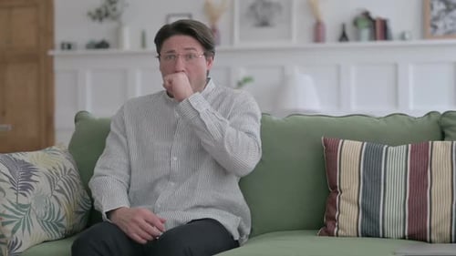 Man Coughing while Sitting on Sofa