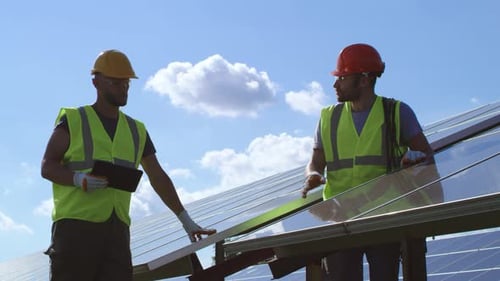 Male Engineers Examining Photovoltaic Panels on Sunny Day