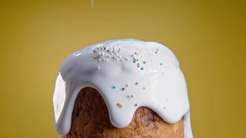 Oster-Kuchendeko mit bunten Dekostreuseln auf gelbem Studiohintergrund