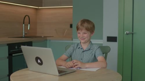 School Child Studying Online Alone Using Laptop at Home
